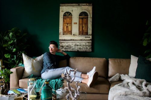 Un étudiant assis dans un salon vide, regardant par la fenêtre et semblant pensif.
